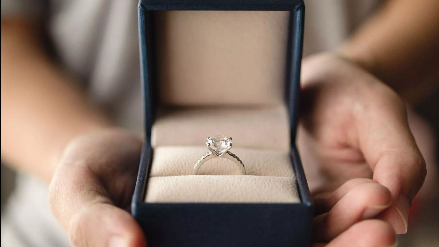 person holding an engagement ring in the box