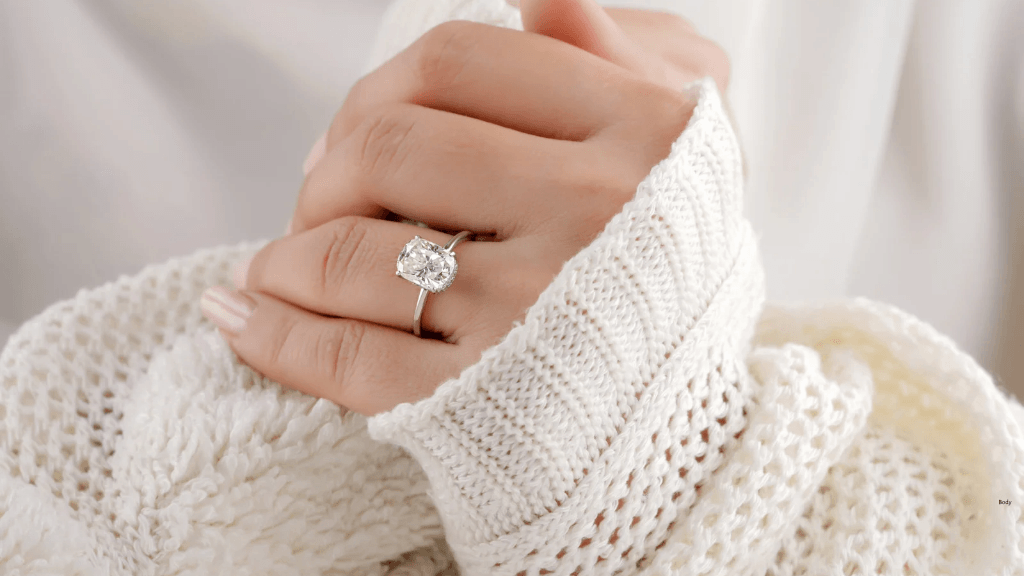 Moissanite engagement ring on woman wearing a white sweater
