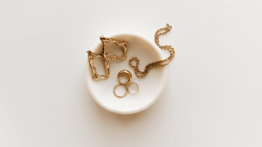 gold jewelry sitting in a white dish