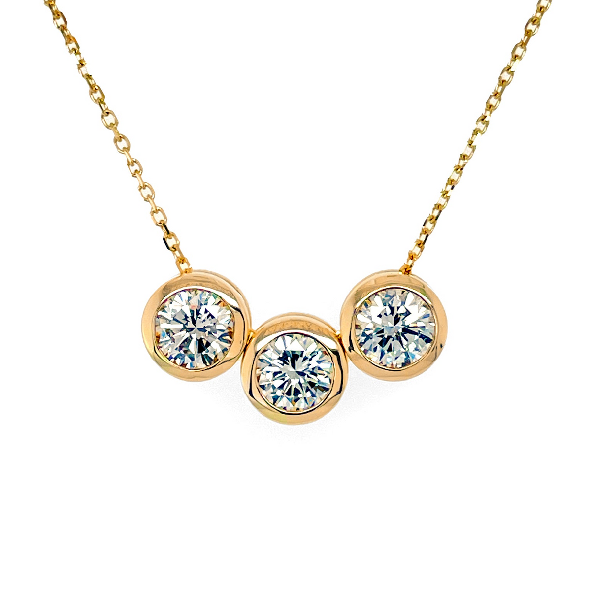 A yellow gold necklace with three bezel set diamonds on a thin gold chain.