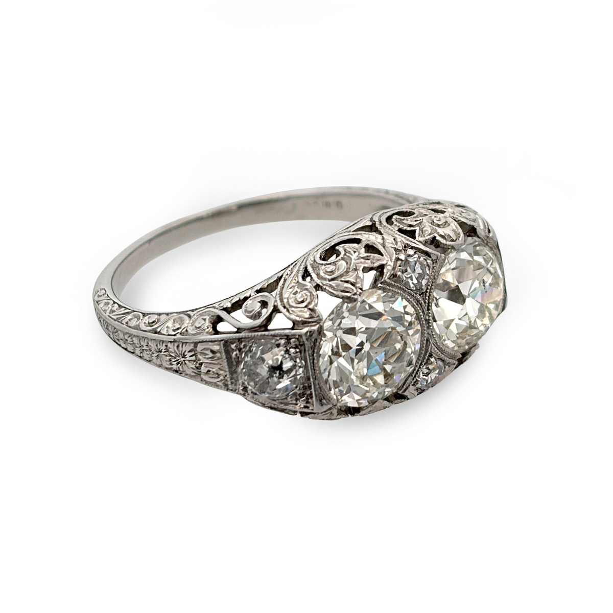 An antique platinum ring with two antique cut center stones with filigree style piercing and engraving.